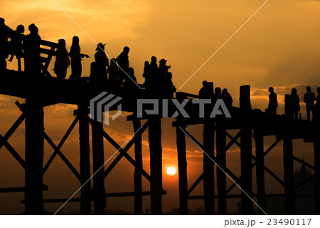 Silhouetted people crossing U bein bridge. 23490117