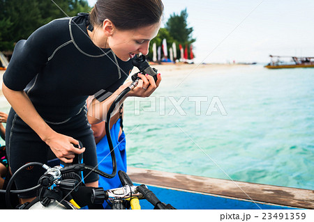 Woman diver testing regulator before scuba diving Woman diver testing regulator before scuba diving 23491359