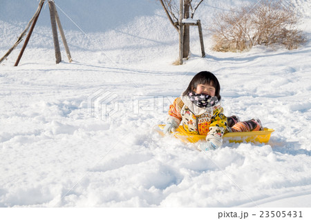 ソリの上に寝そべる子供の写真素材