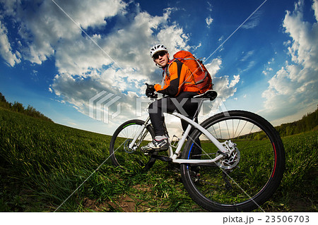 Young man riding on bicycle through deep grass 23506703
