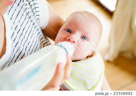 Unrecognizable mother feeding baby son, milk in 23509992