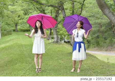 傘をさしながら歩く二人の女性 傘をさしながら歩く二人の女性 23517192
