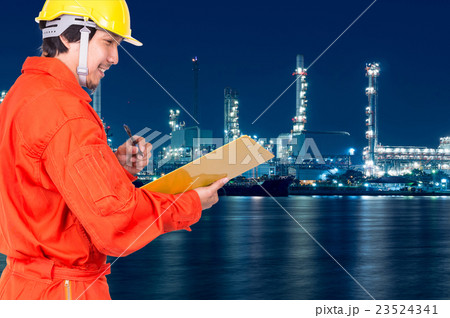 Asian engineers thinking and holding the note pad on Oil and gas refinery or Petrochemical factory at twilight time, industrial concept Asian engineers thinking and holding the note pad on Oil and gas refinery or Petrochemical factory at twilight time, industrial concept 23524341