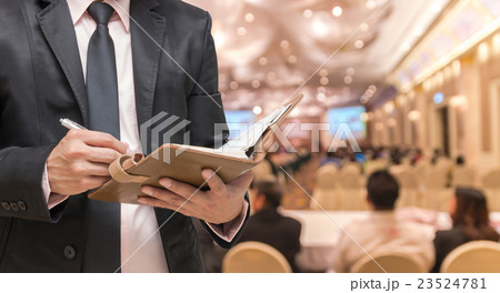 Businessman writing the note book on the Abstract blurred photo of conference hall or seminar room with attendee background Businessman writing the note book on the Abstract blurred photo of conference hall or seminar room with attendee background 23524781