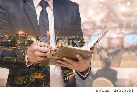 Double exposure of Businessman writing the note book on the Abstract blurred photo of conference hall or seminar room with attendee background Double exposure of Businessman writing the note book on the Abstract blurred photo of conference hall or seminar room with attendee background 23525551