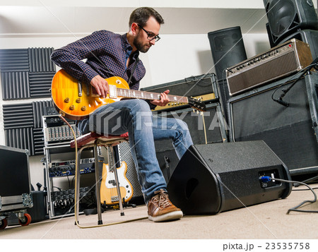 Playing electric guitar in a studio Playing electric guitar in a studio 23535758