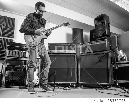 Practicing his electric guitar in a jam room 23535763