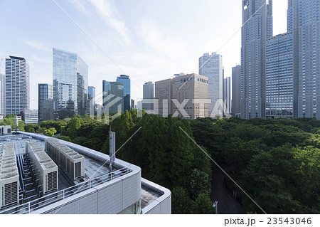 東京都市風景 新宿中央公園と東京都庁 新宿高層ビル群 朝 逆光 ビル屋上 エアコン室外機の写真素材