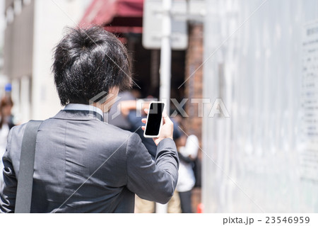 屋外でスマホを見るビジネスマン 23546959