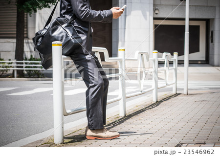 屋外でスマホを見るビジネスマン 屋外でスマホを見るビジネスマン 23546962