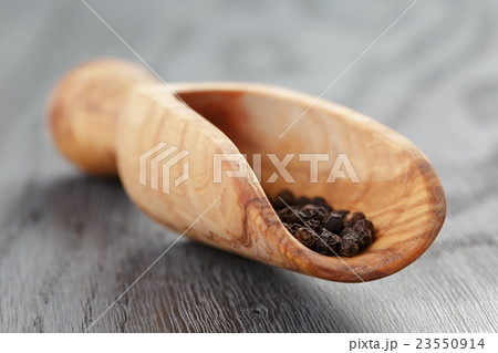 black pepper in olive scoop on wood table black pepper in olive scoop on wood table 23550914