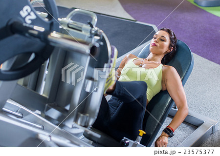 Fit woman working out on leg press machine in gym. Fit woman working out on leg press machine in gym. 23575377