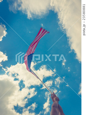 American flag with stars and stripes hold with hands against blue sky ( Filtered image processed vintage effect ) 23580881