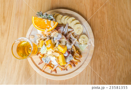 Waffle and fruit with ice cream on table . 23581355