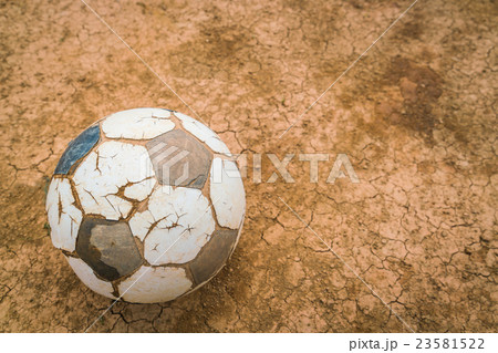 Old soccer ball on Dry and cracked ground texture . 23581522