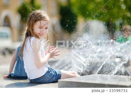 Cute girl playing with a city fountain Cute girl playing with a city fountain 23596731