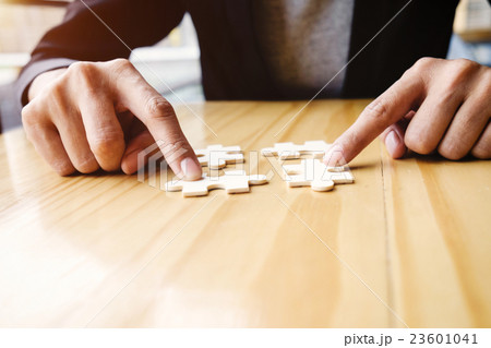 Female hands on a wooden office desk pick puzzle 23601041