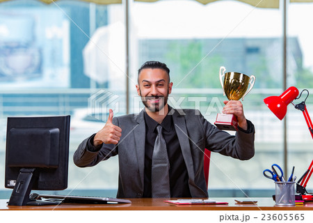 Businessman winning cup trophy in the office Businessman winning cup trophy in the office 23605565