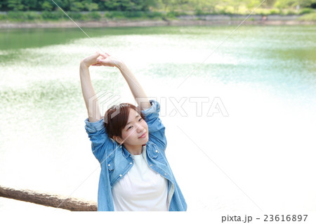 湖の前で背伸びをする若い日本人女性 23616897