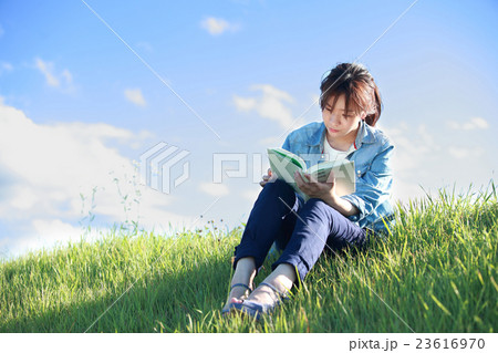 緑の土手で読書をする若い日本人女性 23616970