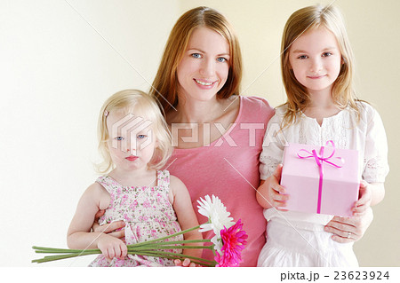 Mother and he daughters giving a gift 23623924