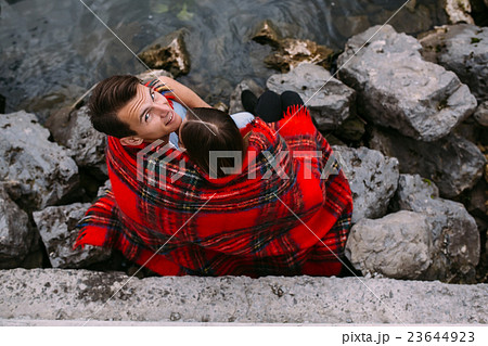 Young beautiful couple sitting on the beach Young beautiful couple sitting on the beach 23644923
