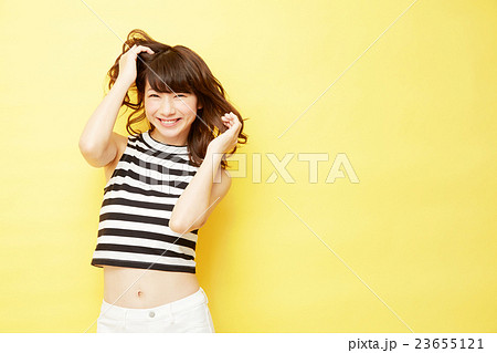 スタジオポートレート 女性 巻き髪 黄色背景の写真素材