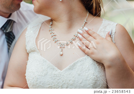 the fat bride wears a necklace around his neck 23658543