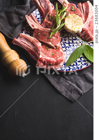 Raw uncooked lamb chops with herbs and spices on 23683004