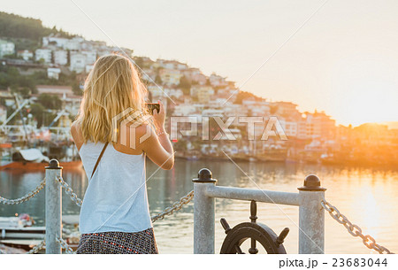 Young blond tourist woman making photo of sunset 23683044