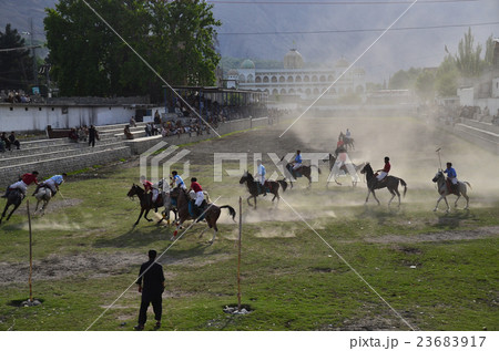 パキスタン ギルギットのポロ競技場と山とモスク ポロの試合で馬に乗りボールを追う選手達の写真素材