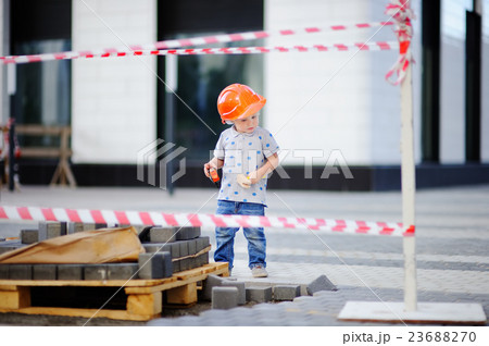 Little builder in hardhats with ruler working outdoors 23688270