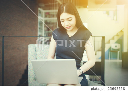 Asian woman sitting and playing a laptop in office Asian woman sitting and playing a laptop in office 23692538