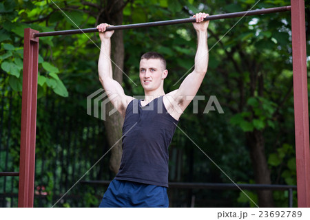 strong man doing pull-ups on a bar outdoor strong man doing pull-ups on a bar outdoor 23692789