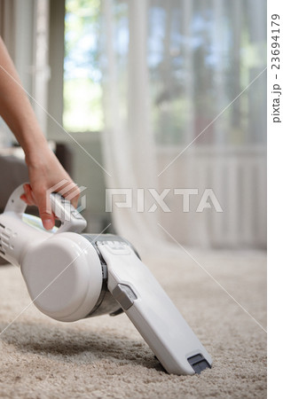 Woman cleaning carpet cordless handheld vacuum Woman cleaning carpet cordless handheld vacuum 23694179