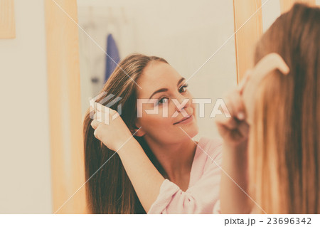 Woman combing her long hair in bathroom Woman combing her long hair in bathroom 23696342