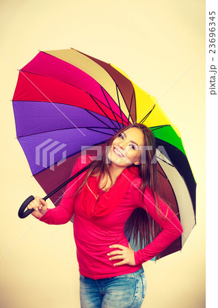 Woman standing under multicolored umbrella Woman standing under multicolored umbrella 23696345