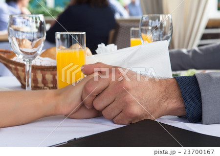 Hands of romantic couple over a restaurant table Hands of romantic couple over a restaurant table 23700167