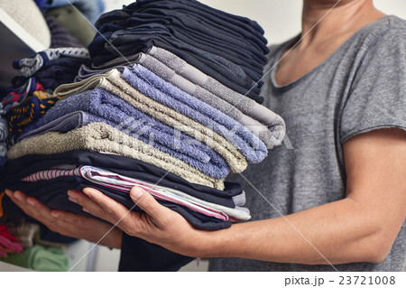 young man with a pile of folded clothes 23721008