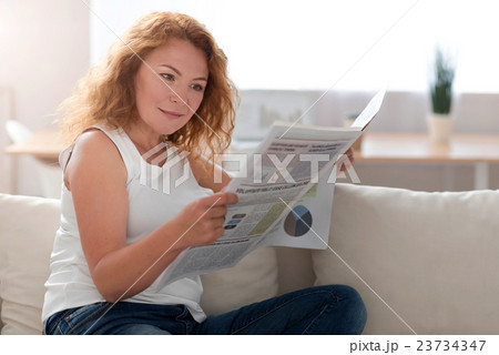 Interested pleasant woman reading newspaper Interested pleasant woman reading newspaper 23734347