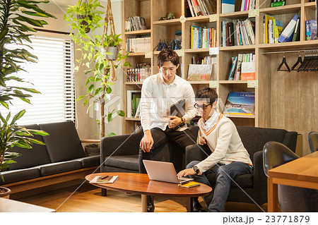 シェアオフィスでソファーに座り打合せをする男性2人 23771879