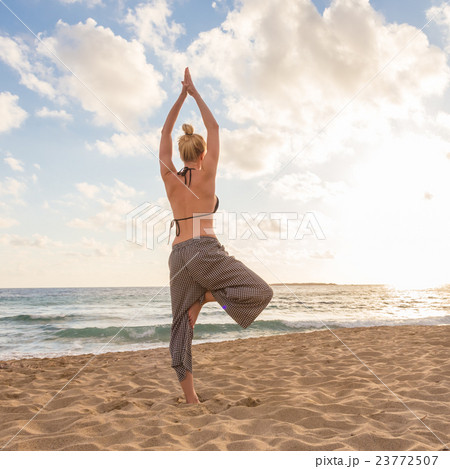 Woman practicing yoga on sea beach at sunset. 23772507