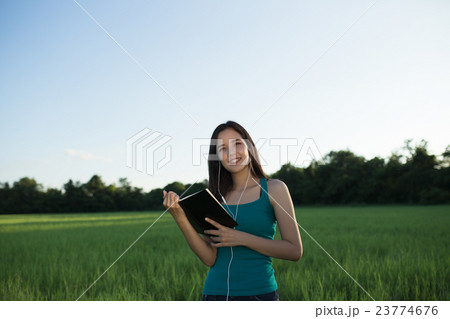 Woman holding book standing in green grass 23774676