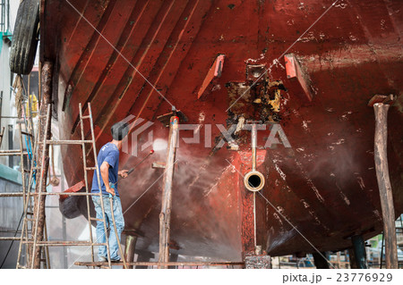 Man working on pressure washer to cleaning boat hull barnacles antifouling and seaweed at the harbor Man working on pressure washer to cleaning boat hull barnacles antifouling and seaweed at the harbor 23776929