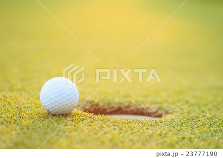 Golf ball on lip of cup in course Golf ball on lip of cup in course 23777190