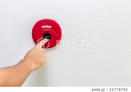 Hand with finger pressing red fire alarm on the wall 23778793