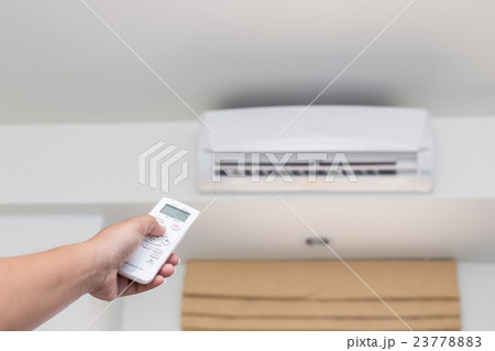 Hand holding remote control directed on the conditioner Hand holding remote control directed on the conditioner 23778883