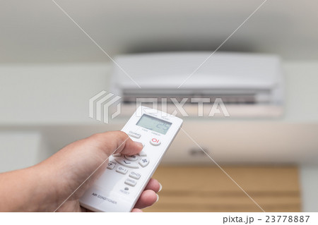 Hand holding remote control directed on the conditioner 23778887