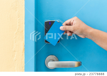 Hand holding blue hotel keycard in front of electric door 23778888