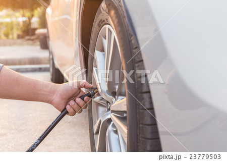Man checking air pressure and filling air to the tires of his car 23779503